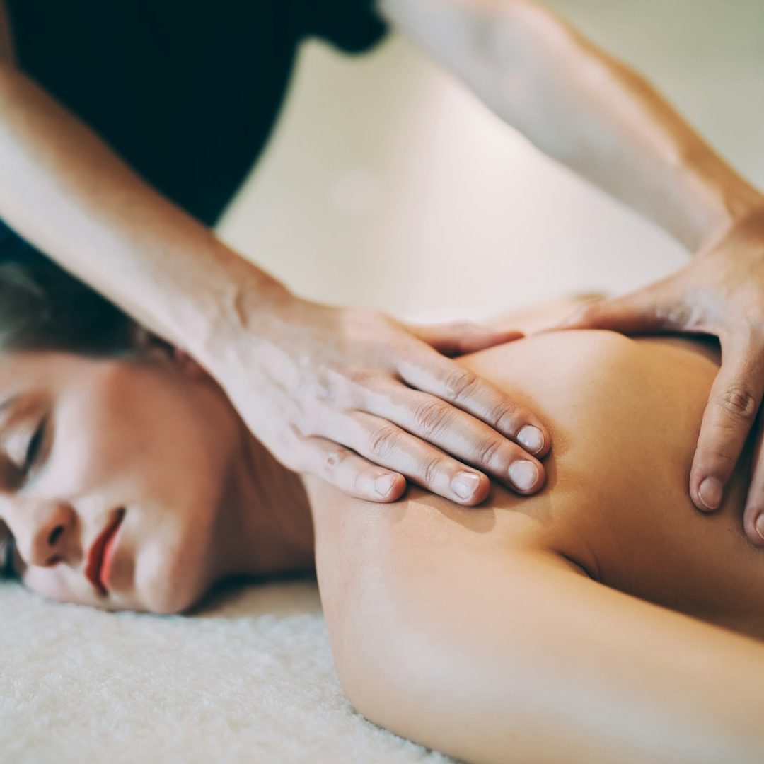 Frau erhält eine entspannende Rückenmassage auf einer weichen Decke.